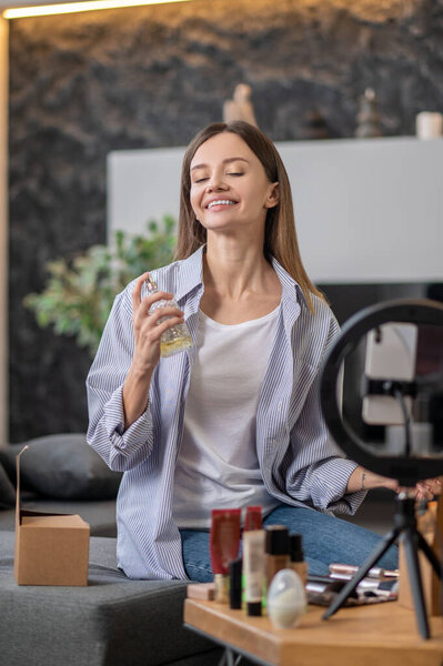 Молодая женщина показывает новый аромат для аудитории в Интернете