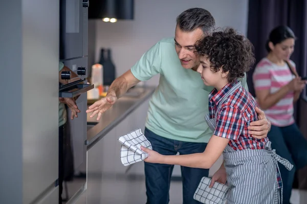 Мужчина показывает, что его сын работает в духовке дома — стоковое фото