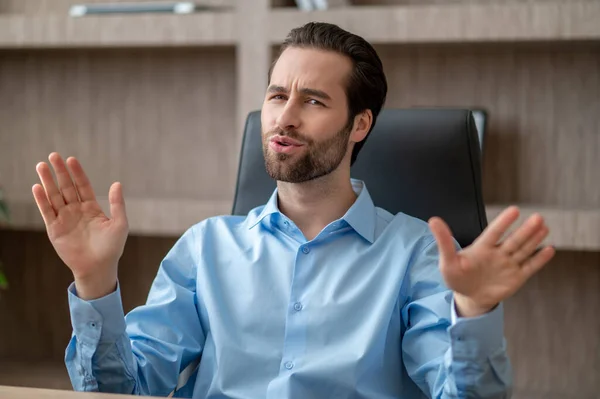 Een man zit op kantoor en kijkt tevreden. — Stockfoto