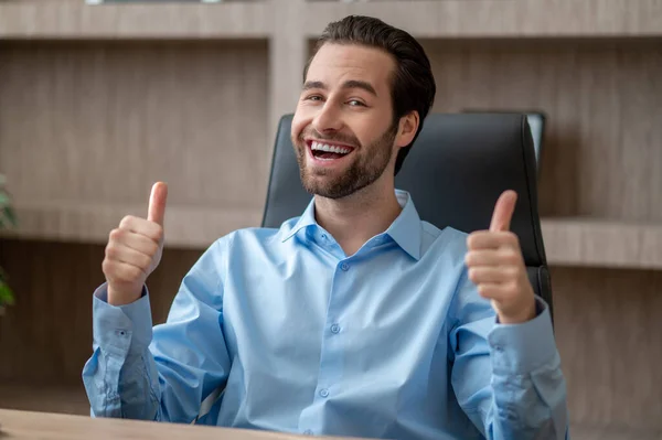 Um homem sentado no escritório e olhando satisfeito — Fotografia de Stock