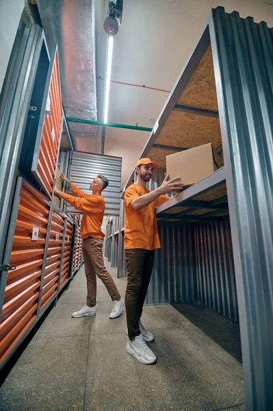 Twee magazijnmedewerkers die goederen in containers stoppen — Stockfoto