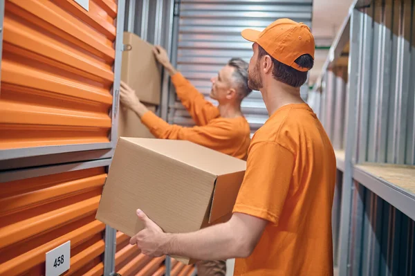 Two Caucasian warehouse loaders stacking boxed goods — Stock Photo, Image