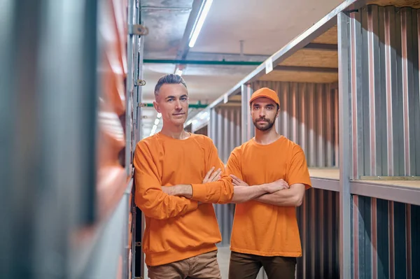 Beroepsbeoefenaar in een opslagplaats en zijn collega staan tussen opslagcontainers — Stockfoto