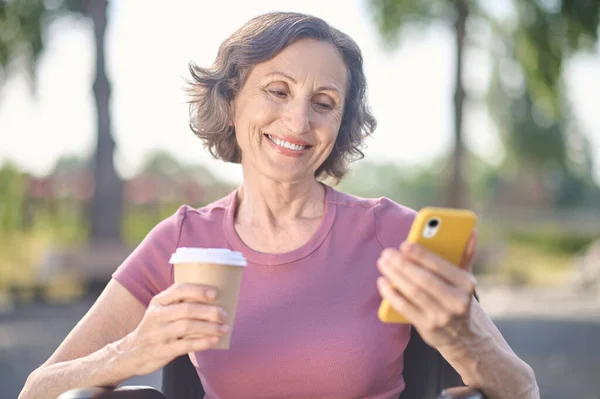 Μια γυναίκα με ένα τηλέφωνο στα χέρια που δείχνει χαρούμενη και χαμογελαστή. — Φωτογραφία Αρχείου
