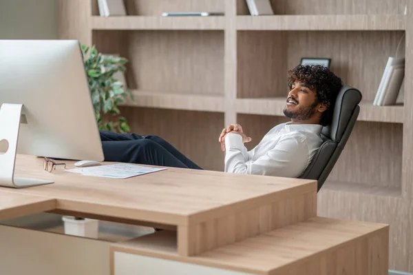 Mladý indický podnikatel sedí v křesle v kanceláři — Stock fotografie