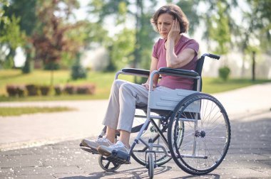 Mutsuz bir bakışla tekerlekli sandalyede oturan orta yaşlı bir kadın.