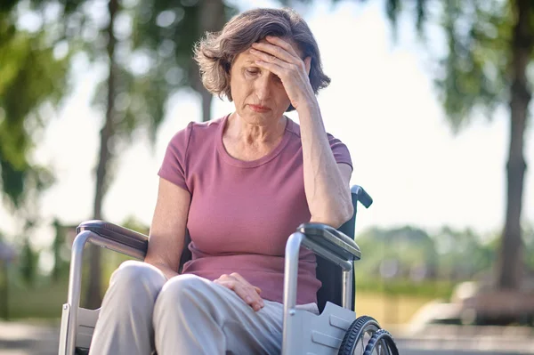 Zdravotně postižená žena středního věku sedící na invalidním vozíku s nešťastným výrazem — Stock fotografie