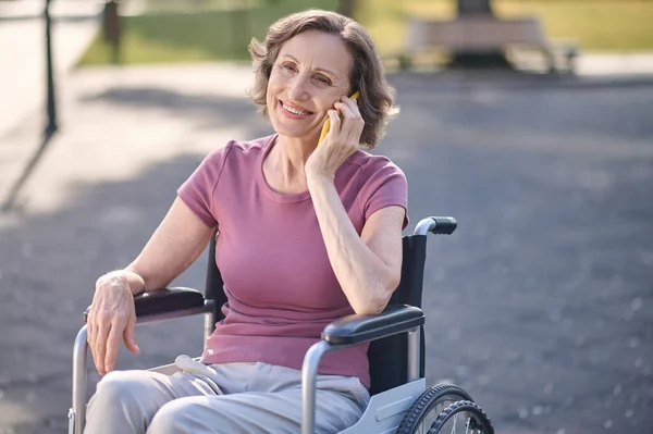 Улыбающаяся женщина на инвалидной коляске разговаривает по телефону — стоковое фото