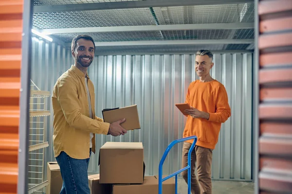 Dos cargadores de almacén alegres posando para la cámara en el trabajo — Foto de Stock