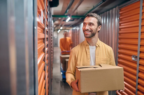 Alegre empleado de almacén y su compañero de trabajo descargando bienes — Foto de Stock