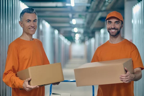 Dos cargadores de almacén que sostienen cajas de cartón y miran hacia el futuro — Foto de Stock