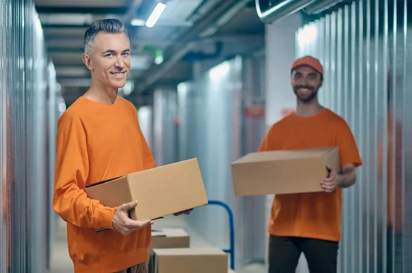 Dos trabajadores sosteniendo mercancías en caja en sus manos — Foto de Stock