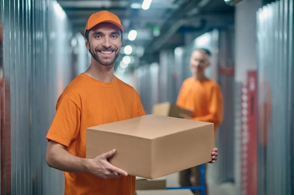 Hombre trabajador y su compañero de trabajo descargar mercancía — Foto de Stock