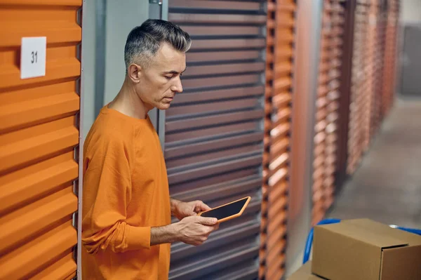 Focused warehouse worker using his gadget in the storage room — Stock Photo, Image