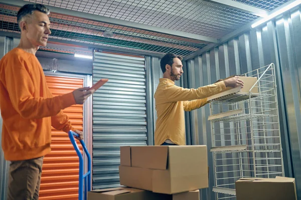 Due uomini in piedi nel magazzino durante lo scarico del carico — Foto Stock