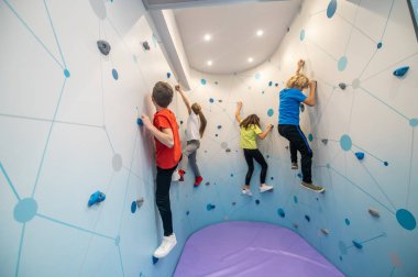 Odaklanmış çocuklar duvara tırmanıyor.