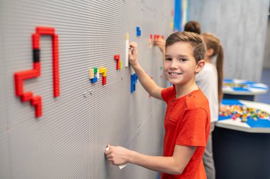 Çocuk kameraya bakarak lego oynuyor..