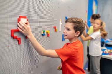 Oğlan ve kızlar duvarda lego yapbozu yapıyor