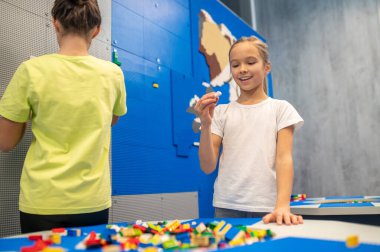Lego inşaatçısının detaylarına neşeyle bakan bir kız.