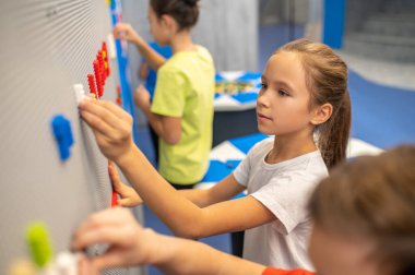 Lego parçasını duvara yapıştıran kız