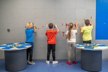 Lego detaylarını duvara iliştiren çocukların arka planı