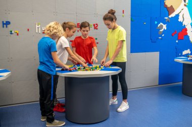 Çocuklar lego parçalarıyla masanın etrafında duruyorlar.