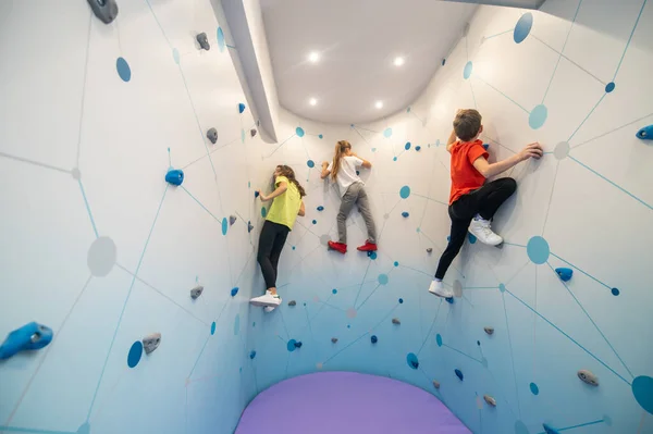 Boy and two girls climbing wall indoors — Stock Photo, Image