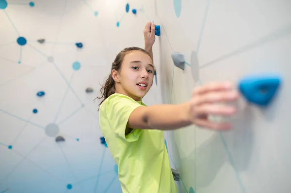 Girl on wall with effort stretching hand to ledge — Stock Photo, Image