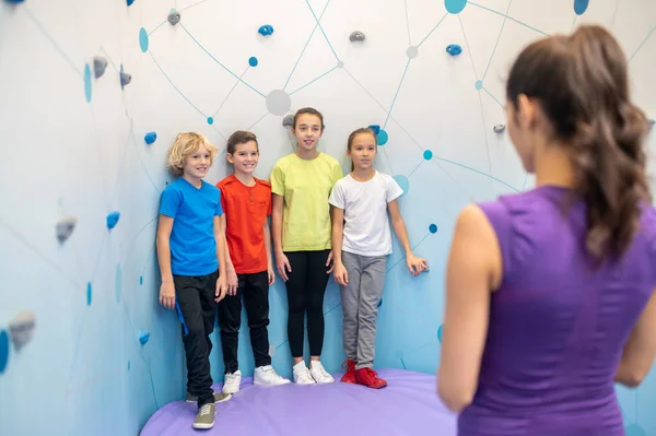 Children standing near climbing wall listening to coach — Stock Photo, Image