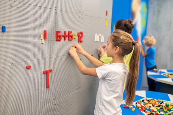 Chica con amigos cerca de la pared jugando lego —  Fotos de Stock