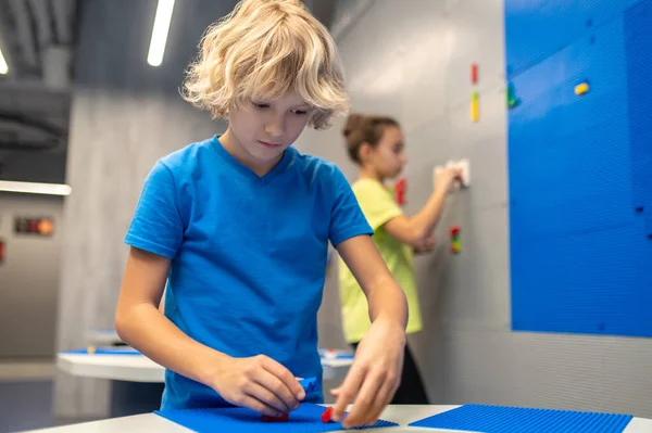 Boy looking carefully attaching lego pieces — Stock Photo, Image