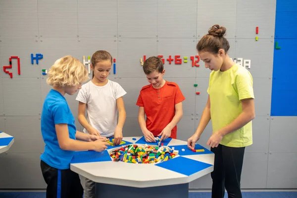 Niños jugando con lego de pie alrededor de la mesa —  Fotos de Stock