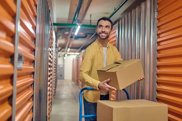 Joyous young male worker unloading items indoors — Stock Photo, Image