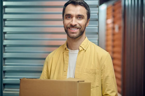 Cargador alegre sosteniendo una caja de cartón y mirando hacia el futuro — Foto de Stock