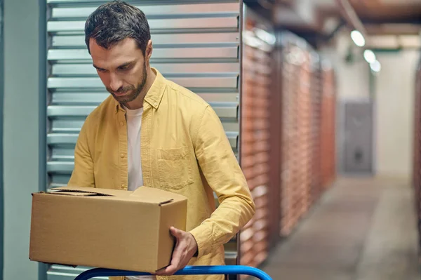 Trabajador concentrado poniendo mercancías en caja en el carro — Foto de Stock