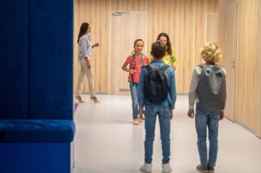 Kameraya arkası dönük oğlanlar ve içeri giren kızlar.