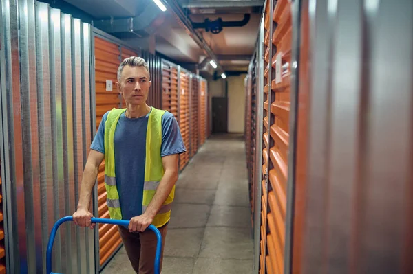 Serious warehouse operative standing among shipping containers — Stock Photo, Image