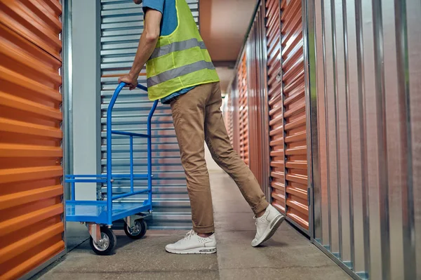 Trabalhador masculino empurrando um carrinho de armazém vazio — Fotografia de Stock