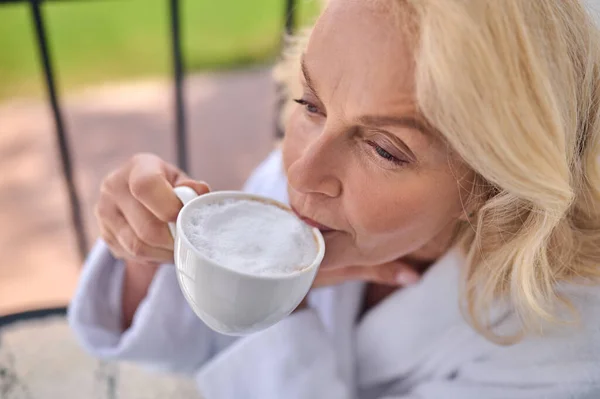 Une femme blonde ayant cappuccino matin au balcon — Photo