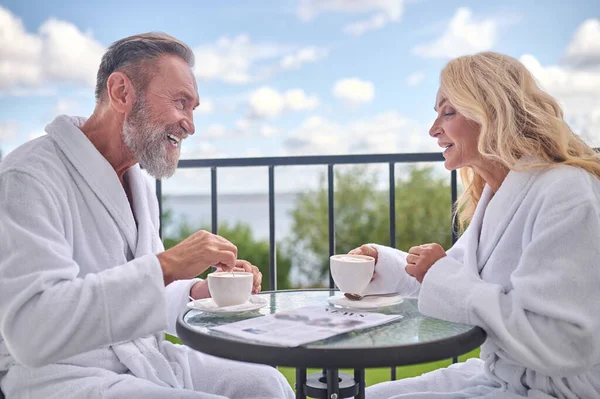 Um casal de roupões whote tomando café da manhã na varanda — Fotografia de Stock