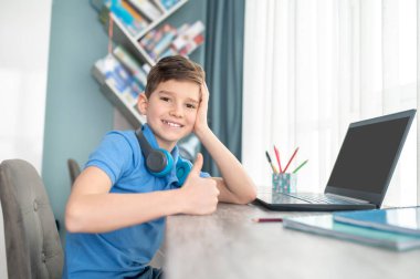 Odasında oturan neşeli çocuk Masaüstüne yaslanmış