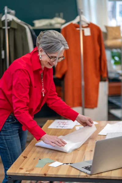 Tevreden vrouw verpakking kleding aan tafel in de winkel — Stockfoto