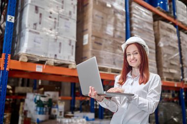 Dizüstü bilgisayarda çalışan bir kadın kameraya bakıyor.