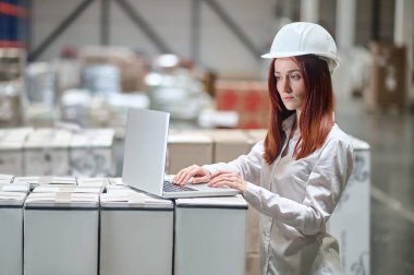 Depoda dizüstü bilgisayara bakan bir kadın.