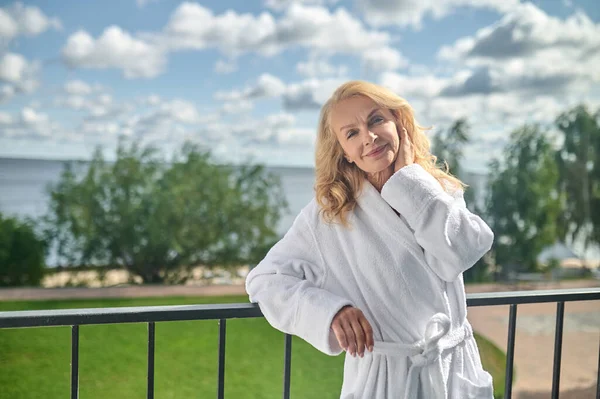 Blondýnka v bílém rouchu, stojící na balkóně — Stock fotografie