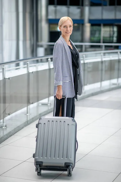 Frau mit Koffer steht im Terminal — Stockfoto