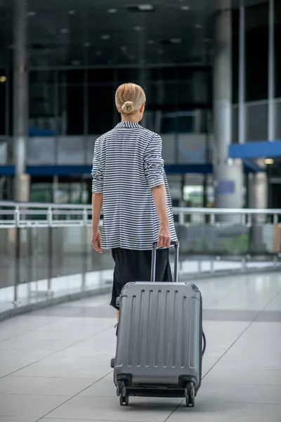 Жінка ходить з валізою ззаду на камеру — стокове фото