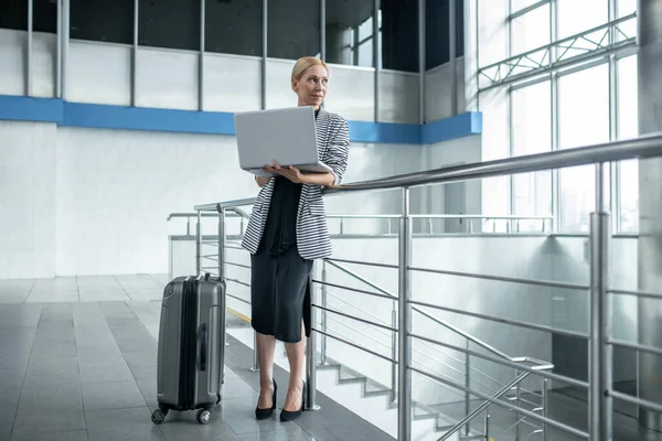 Frau mit Laptop steht neben Koffer im Terminal — Stockfoto