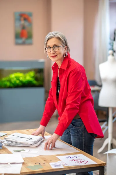 Mujer elegante de pie cerca de la mesa mirando a la cámara — Foto de Stock