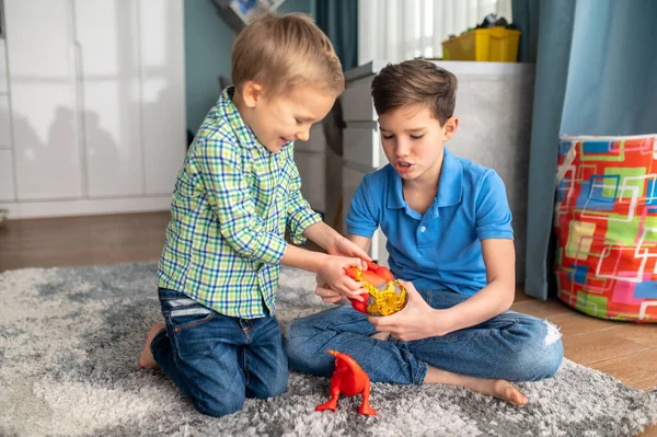 Two kids with rubber animal figures sitting in a room — Stock Photo, Image